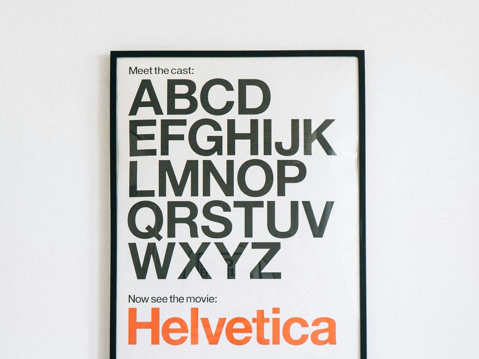 Framed poster of the Helvetica alphabet on a white wall