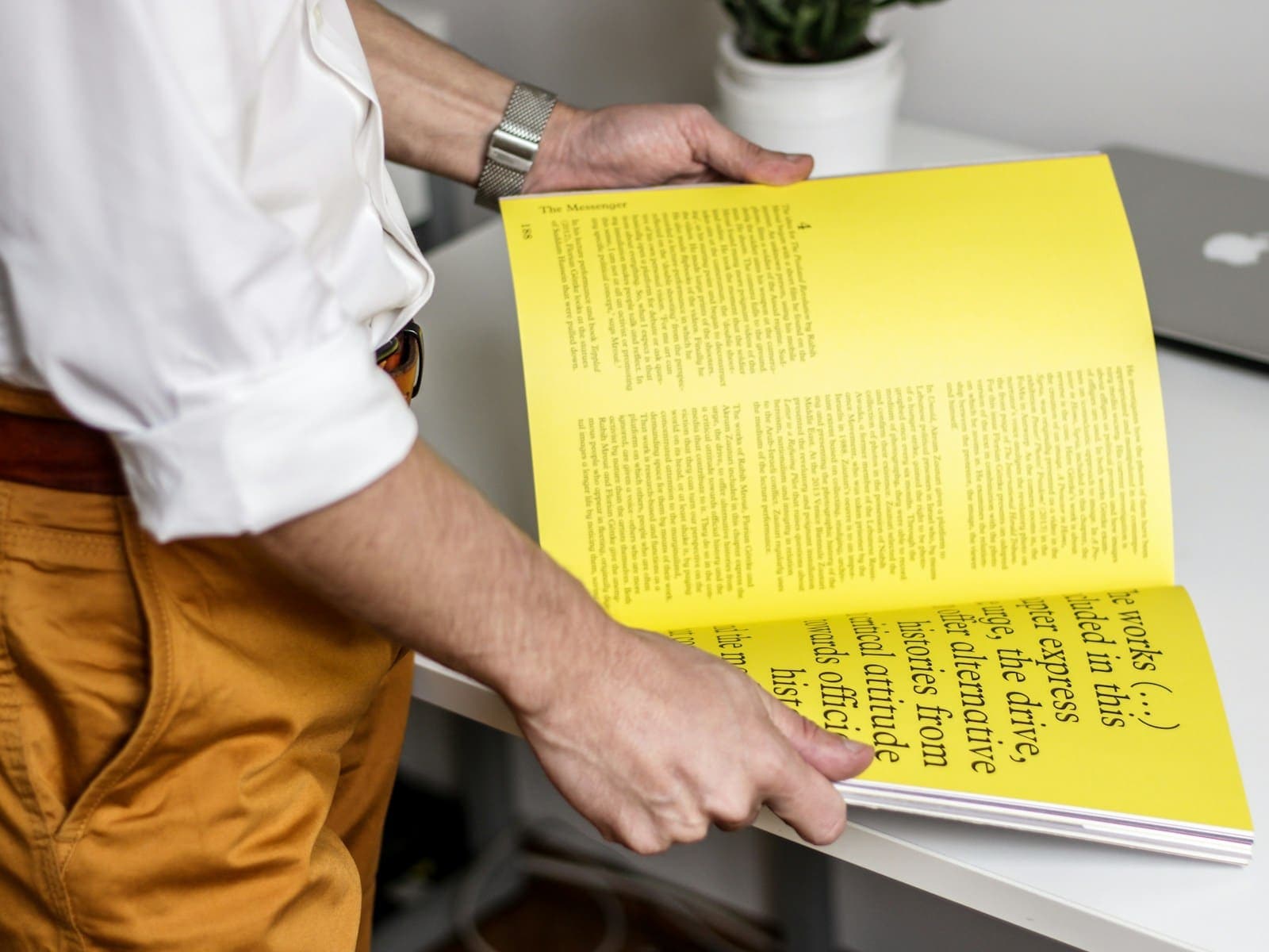 Person leafing through a yellow magazine on a desk