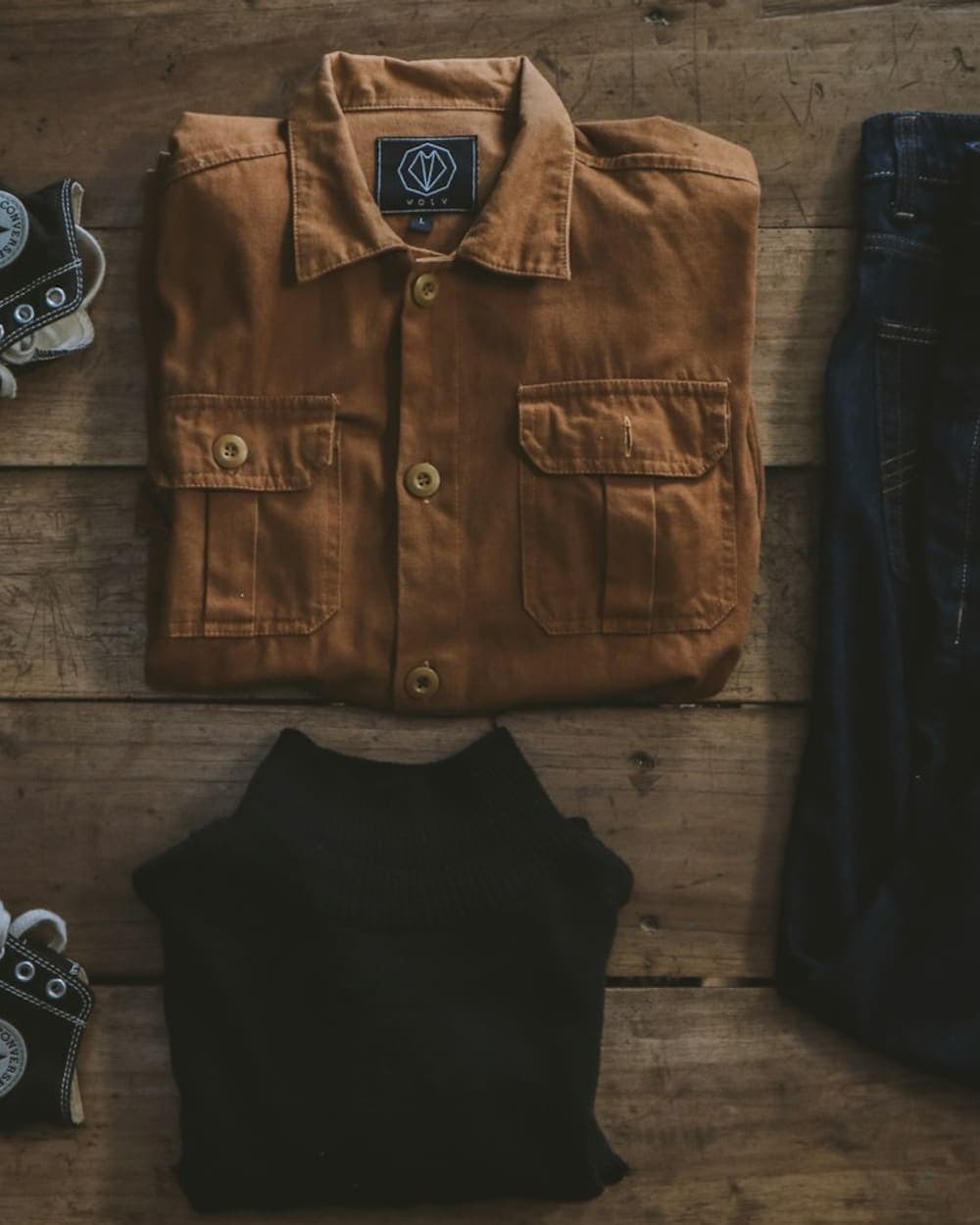 Tan work jacket laid flat with black jeans and sneakers